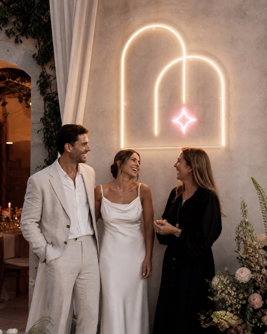 Bruidspaar en eventstylist naast het Double Vow neonconcept